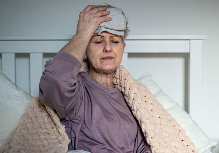 senior woman with headache in bed at home