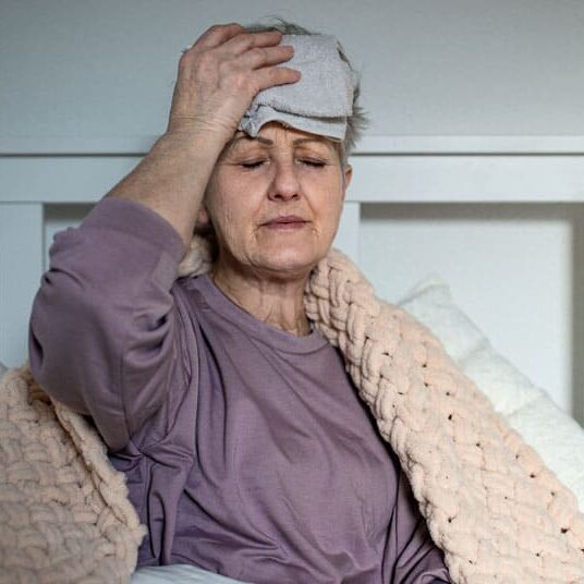 senior woman with headache in bed at home